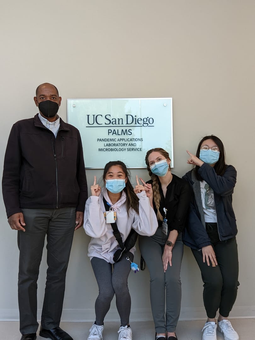 The Pride Laboratory team at UC San Diego, by the PALMS — Pandemic Applications Laboratory and Microbiology Service — sign